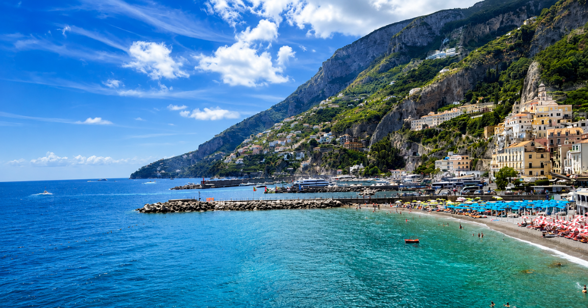 Village de la côte amalfitaine avec plage et parasols au pied de falaises escarpées